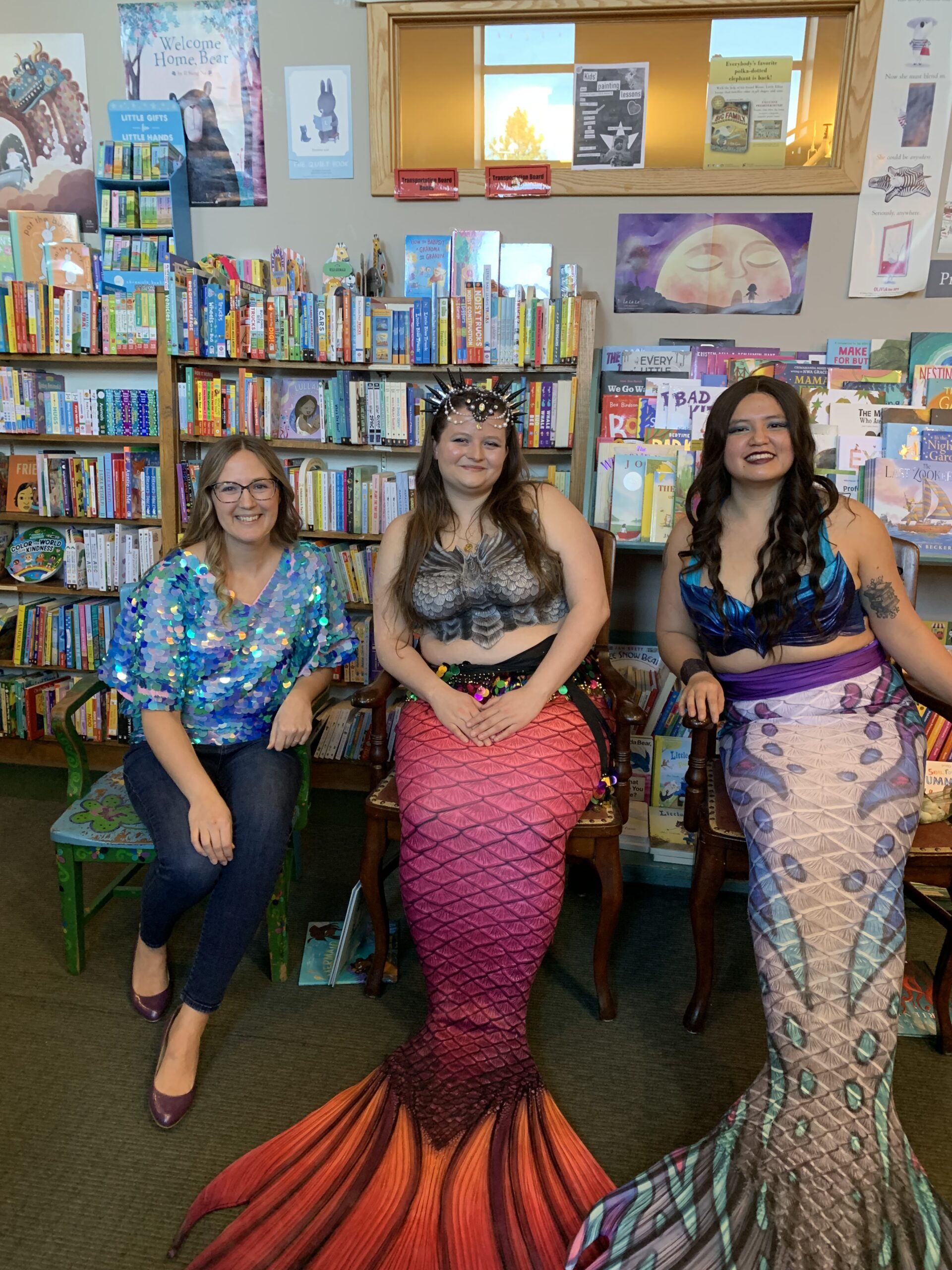 Eija in a sparkly mermaid top next to two amazing mermaids in Aunties Books